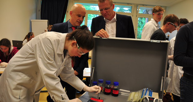 Schulleiter Dr. Christian Gefert und der Geschäftsführer Dirk Greshake von AstraZeneca freuen sich über das mobile Labor