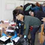 Eine Freiwillige hilft einem Flüchtling dabei passende Schuhe zu finden.