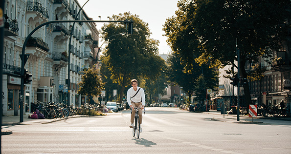 Junger Mann fährt auf Fahrrad durch Hamburg. Eine typische Straße in Eimsbüttel