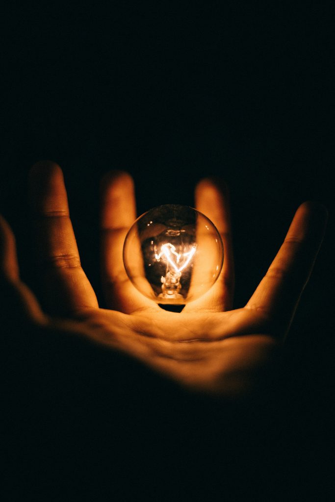 Energiekosten - sanftes Licht einer Glühbirne scheint auf eine Handfläche