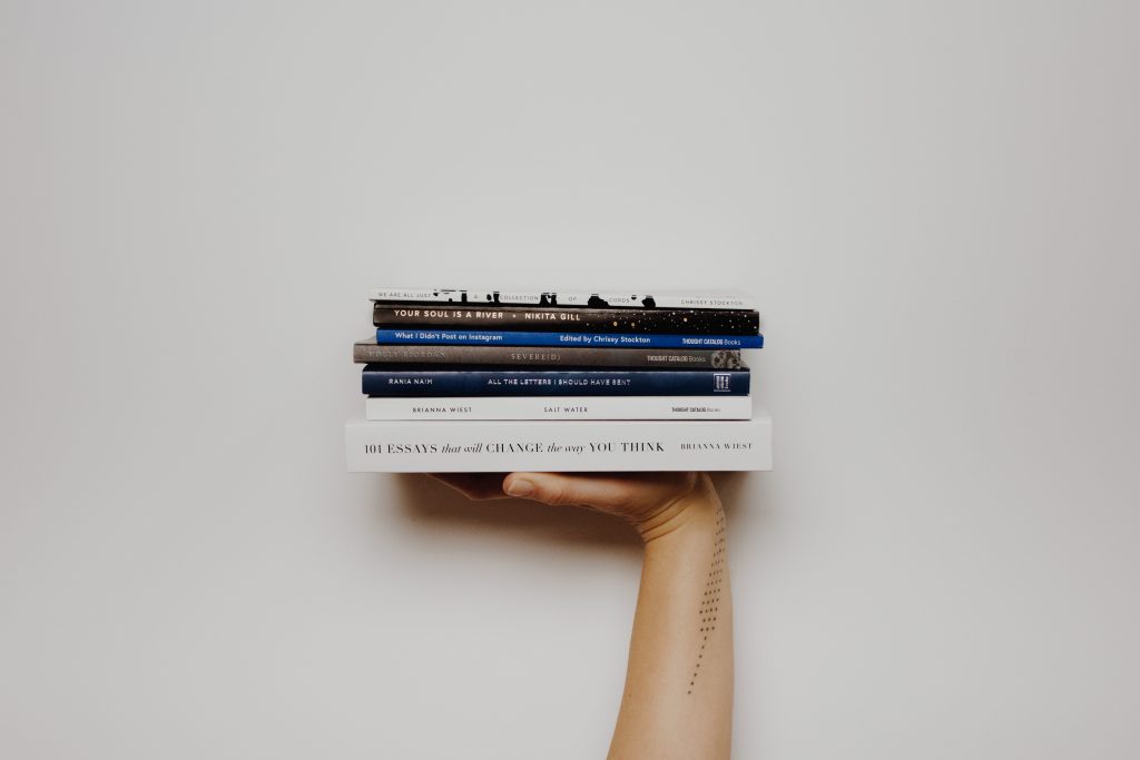 Hamburg stemmt erneut die Lange Nacht der Literatur.- // Foto:Thought Catalog auf Unsplash : Bild zeigt eine hand auf der ein Stapel Bücher liegt.