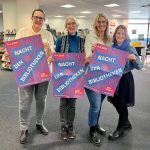 Vier Mitarbeiterinnen der Stadtbücherei Wedel mit Plakaten zur Nacht der Bibliotheken