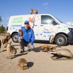 Ein Mitarbeiter des NABU mit einigen Tierpräparaten vor dem FuchsMobil